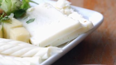 Yumuşak beyaz peynir ve canlı sebzeler bir tabakta güzelce dizilmiş.
