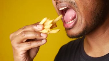 Bireyin, nefis gevrek patates kızartmasının tadını çıkarırken çekilmiş yakın plan bir görüntüsü.