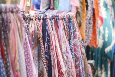 Canlı, renkli eşarplar güzel işlenmiş ve hareketli bir pazarda asılı.