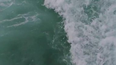 Okyanus dalgaları beyaz köpükle çarpar, doğanın ham enerjisini ve ihtişamını yakalar.