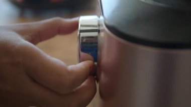 Şık ve şık bir mutfak aletinin kadranını ustalıkla ayarlayan bir el.