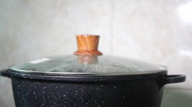 Mutfak tezgahında düzgünce dinlenen kapaklı geleneksel bir tencere.