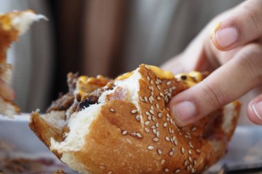 Lezzetli susamlı burgerin tadına varan birinin canlı bir yakın çekimi.