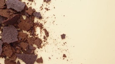 Parçalanmış siyah çikolata parçaları tarafsız bir zemine güzelce saçılmış.