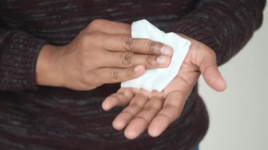 Adam ıslak mendille ellerini dezenfekte ediyor.