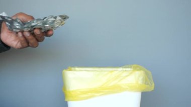 Kullanılmamış bir ilacı güvenli atık imhası için sarı bir kutuya atan bir insan.