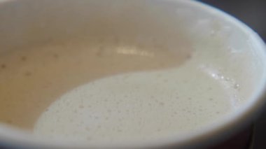 Bu, beyaz bardakta zarif bir şekilde servis edilen kremalı kahve içeceğini gösteren yakın çekim görüntüsü.