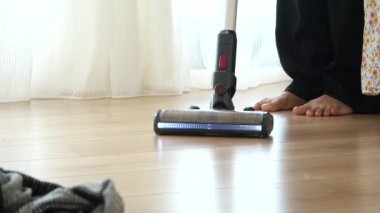 Ahşap zemin yüzeyini süpüren bir bireyin detaylı yakın plan görüntüsü.