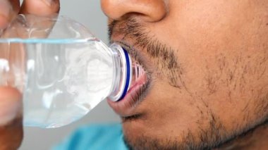 Detaylı bir yakın çekim görüntüsü bir bireyi temel su ihtiyacı için su içerken yakalıyor.
