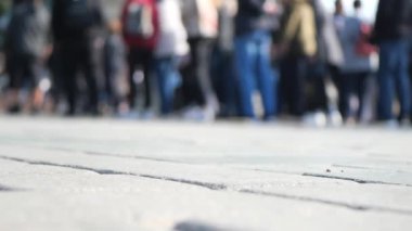 Biraz bulanık bir perspektif, asfalt bir yüzey üzerinde birlikte duran büyük bir insan topluluğunu gözler önüne serer.