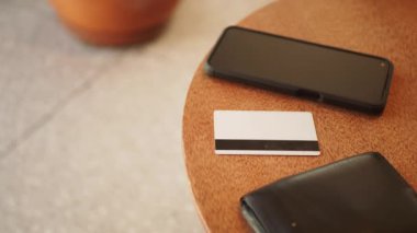 Bir akıllı telefon ve kafeterya masasında duran bir kredi kartı.