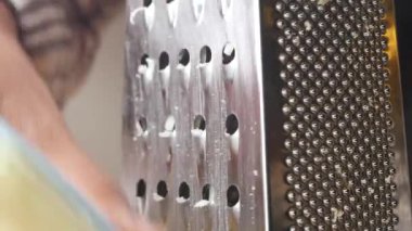 Taze rendelenmiş peynir ahşap bir yüzeyde duran metal rendesinin yanına güzelce istiflenmiş.