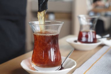 Taze demlenmiş çayların zarif cam bardaklara dikkatle döküldüğü hoş bir manzara.