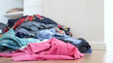 Düzensiz kıyafet parçaları ahşap zemin yüzeyine kaotik bir şekilde dağılmış.