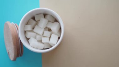 Keyifli beyaz şeker küpleriyle dolu konteynır canlı bir zemin oluşturur.