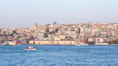 Huzurlu bir rıhtım manzarası teknelerin altını çiziyor ve yakınlardaki büyüleyici bir şehir silueti