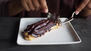 Bu görüntü, zengin bir çikolatalı tatlıyı dikkatlice bir çatalla dilimlenirken gösteriyor.