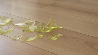 Parlak yeşil cam parçaları ahşap zemine saçılmış, ışığı güzel yansıtıyor.