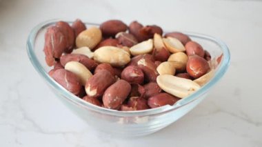 Ağır çekimde kabuklu fıstıkları bir kaseye koyuyor. ,