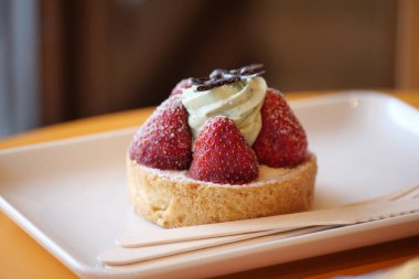 Lezzetli bir çilekli turta üzerine yeşil krema ve lezzetli bir ikram için zengin çikolata.