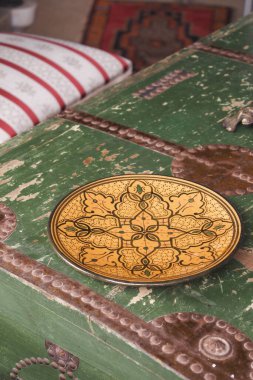 Şaşırtıcı bir şekilde işlenmiş pirinç levha antika yeşil bir sandığın üzerinde zarif bir şekilde duruyor.