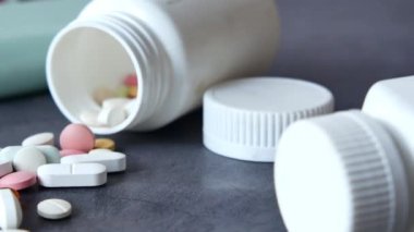 Çevredeki çeşitli beyaz şişelere renkli haplar serpiştirilmiş.