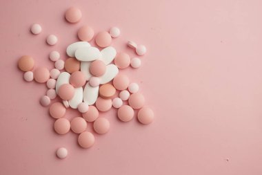 Yumuşak pembe bir yüzeye saçılmış pembe ve beyaz hapların canlı bir karışımı göz alıcı bir sanat yaratıyor.