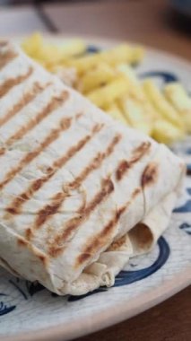 Kızarmış burrito ve kızarmış patates, yükseltilmiş bir yemek için dekoratif bir tabakta servis edilir.