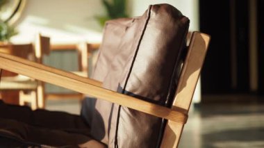 Yakın plan bir resim modern ahşap bir sandalyede güzel bir kahverengi deri yastığı gösterir.