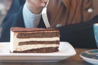 Tadı güzelleşen kremalı bir dilim çikolatalı pastanın tadını çıkarıyorum.