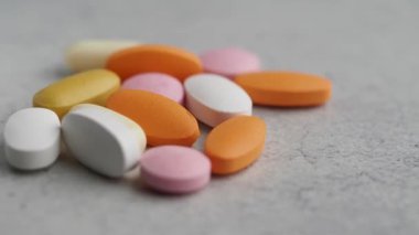 Gri arka plana yayılmış çeşitli tablet ve kapsüllerden oluşan renkli ve canlı bir çeşitlilik.