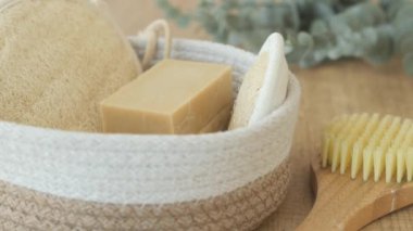 Tahta bir yüzey üzerinde sabun, vücut fırçası, lif ve okaliptüs içeren doğal spa seti..