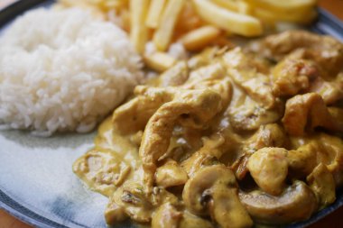 Lezzetli körili tavuğun tadını çıkarın. Pilav ve kızarmış patatesle servis edilir. Tatmin edici bir yemek.