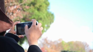 Bir insan doğanın güzelliğini yakalamak ve takdir etmek için akıllı telefonu yukarıda tutar.