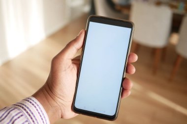 Boş ekran ile akıllı telefonu tutan bir elin yakın çekimi, en küçük tasarımı vurguluyor.