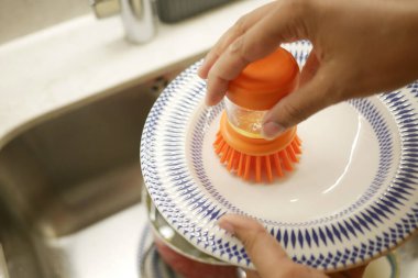 Bir insan mutfakta kase ovalıyor, temizlik ve hijyen standartlarını sağlama alıyor.