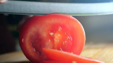 Canlı, olgun bir domates ustalıkla dilimlenerek sulu iç ve taze kırmızı rengini sergiliyor.
