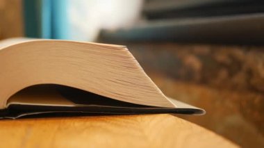 Ahşap bir masada, sayfalarını ve omurgalarını yakalayan açık bir kitabın yakın plan görüntüsü..