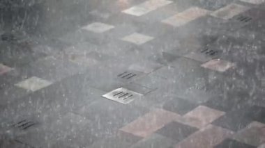 Islak kiremitli kaldırımda güzel bir şekilde yağmur ve kentsel yansımalar sergileniyor.