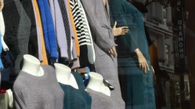 Bir butik vitrininde çeşitli şık giyim seçenekleri güzelce sergileniyor.