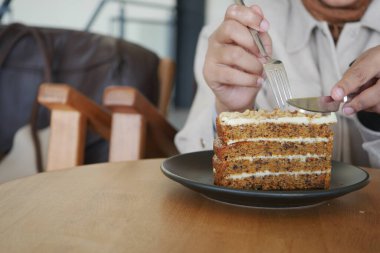 Güzel bir kafede havuçlu keki ustalıkla dilimleyen birinin yakın çekimi.