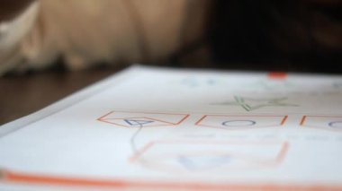 Genç bir çocuk, yaratıcı bir şekilde doldurulmuş bir defter sayfasına neşeyle renkler ve şekiller çizer.