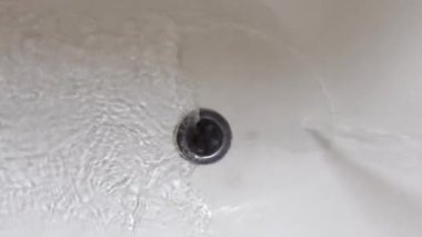 Sakin su, güzel, sakin bir banyo ortamındaki bir drenaja doğru zarif bir şekilde akıyor.