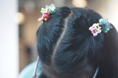 Bu resim renkli kliplerle süslenmiş bir çocuğun hoş saç modelinin yakın çekimini sunar.