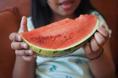Genç bir çocuk neşeyle elinde taze, canlı ve sulu bir karpuz tutuyor.