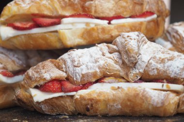 Lezzetli bir ikram için olgun çilek ve krem peynirle dolu taze bir kruvasanın tadını çıkarın.