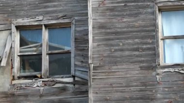 Yıpranmış ahşap bir duvarın detaylı bir yakın çekimi kırık ve eski pencerelerini gösteriyor.