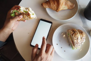 Masanın üzerine iki ayçöreği ve modern bir akıllı telefon yerleştirilmiş rahat bir yemek.