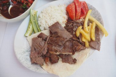 Kuzu çeviren kebap, pirinç ve patates kızartması tabakta. ,