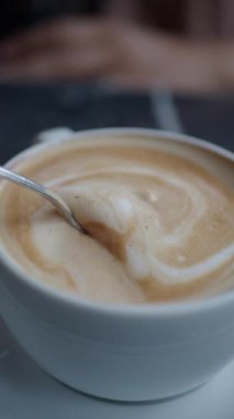 İnsan, kaşıkla kahve karıştırır.